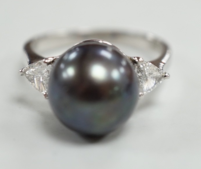 A modern 750 white metal, single stone Tahitian pearl and two stone trillion cut diamond set ring, size O, gross weight 5.6 grams.